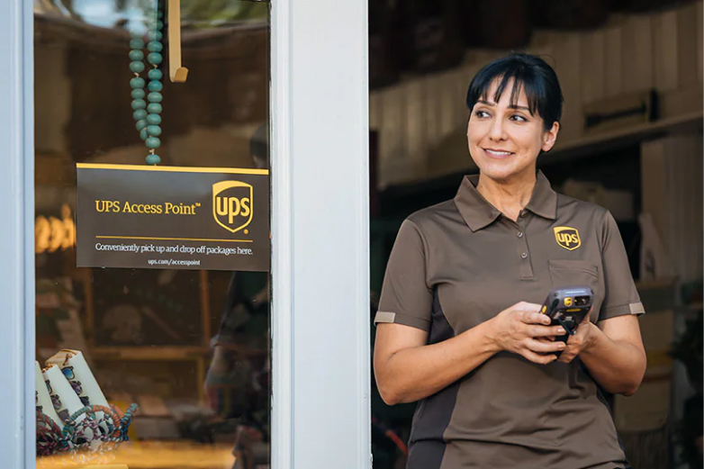 Un employé UPS souriant se tient près de la porte d’un point d’accès UPS.