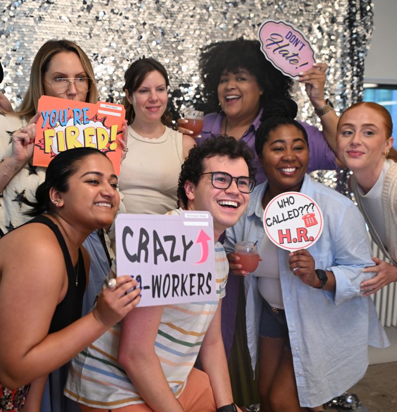 A smiling group of Rokt interns holding funny placards